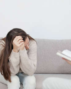 Woman sitting on sofa at a pyschologist's office.