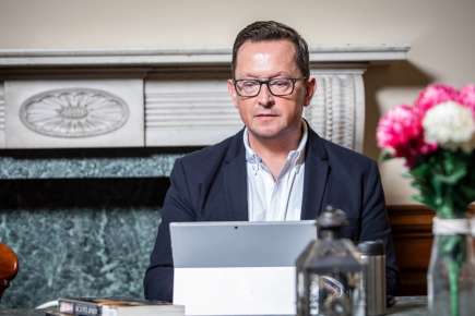 Man sitting at his desk typing on his tablet device.