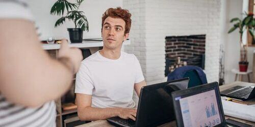 Man sat at a table working on a laptop. 