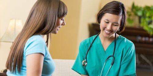 Two women, one wearing scrubs.