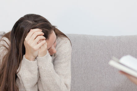 Woman sitting on sofa at a pyschologist's office.