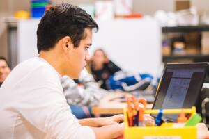 a man in a white long-sleeved tee shirt using a black laptop computer