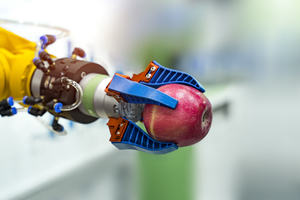 Robotic arm holding an apple in a science lab 