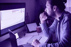 Male professional sat at a desk looking at graphs on a computer screen