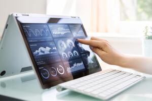 A lady touches a white tablet device screen with her finger in a kitchen setting.