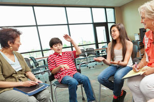 Children sit in a circle, interacting with teachers