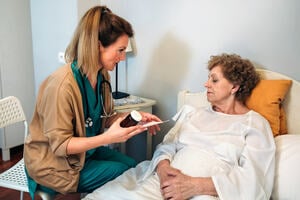 Patient sitting in front of a doctor and reading the label on a bottle of pills in his hand.