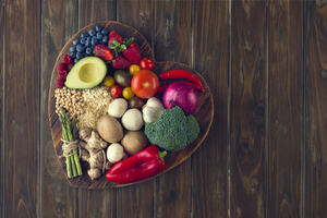 Healthy food with fruit, vegetables, grains and high fibre foods on a heart shape cutting board in a rustic wood textures background. These are the food that provide nutritions to prevent age-related disease such as chronic conditions.