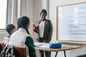 Teacher standing at the front of the classroom with a book in hand